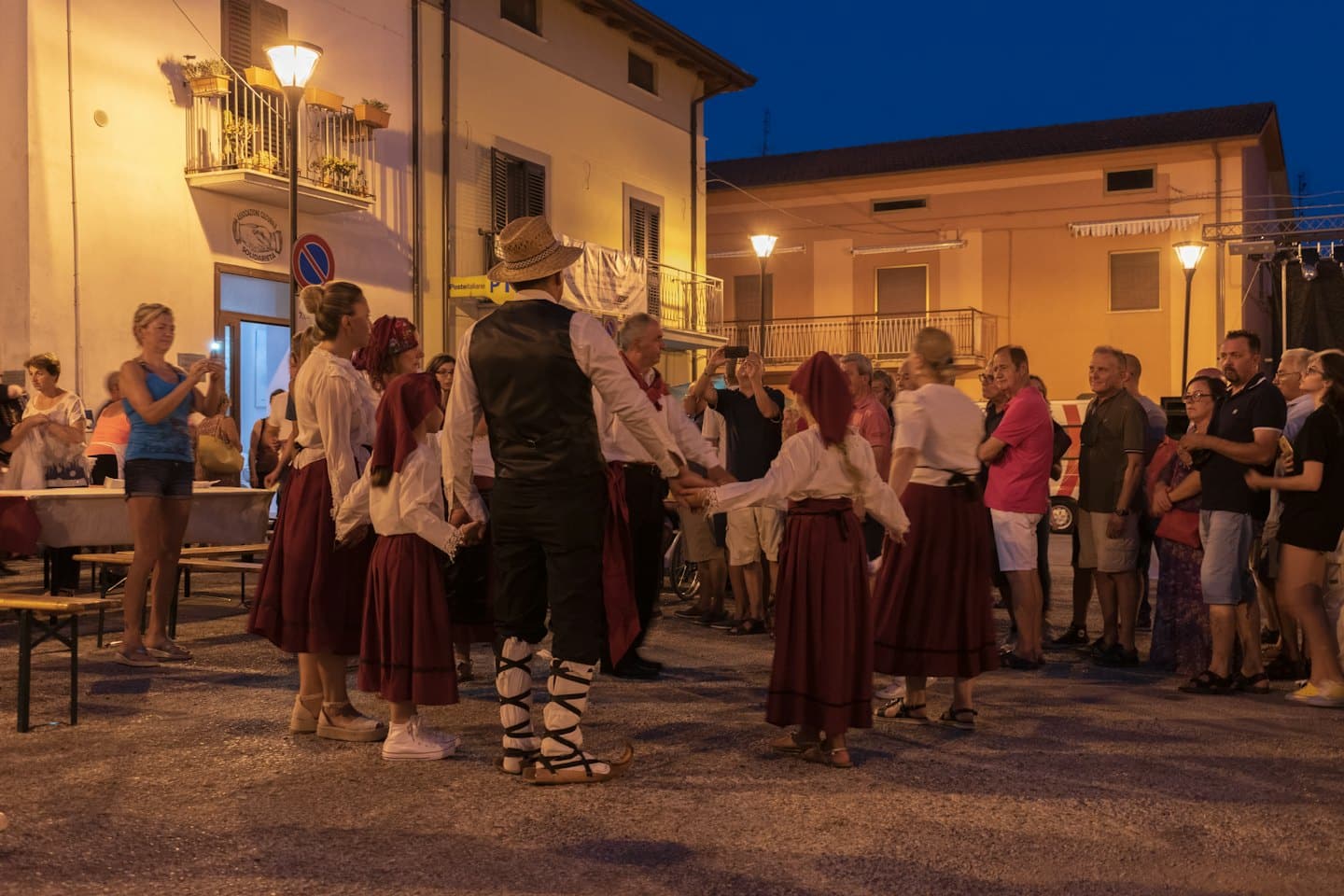 People in traditional costumes dance in a village circle.