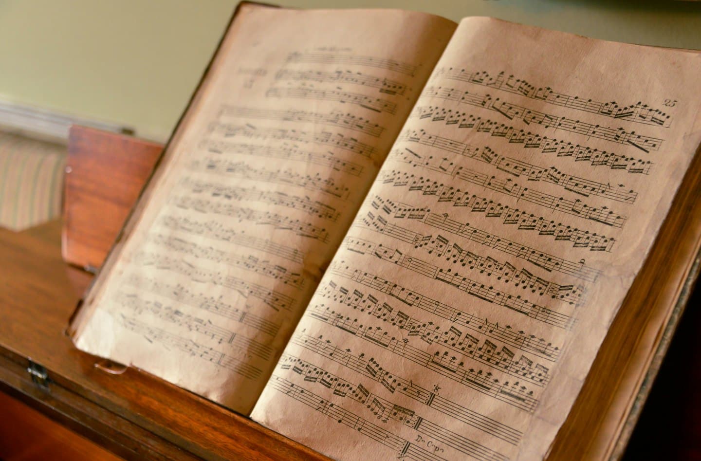 Antique music book with handwritten notes on a wooden stand.